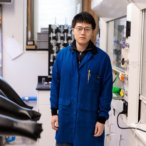 Yahao Dai next to a row of gloveboxes in lab